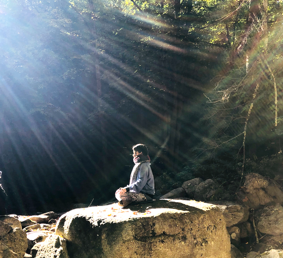 Woman sitting on a rock and meditating near Honor's Haven Retreat