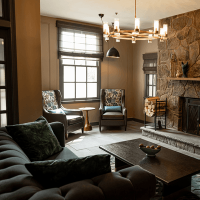 Lounge room featuring a stone fireplace beside plush armchairs and a dark sofa at La Tourelle Hotel and Spa