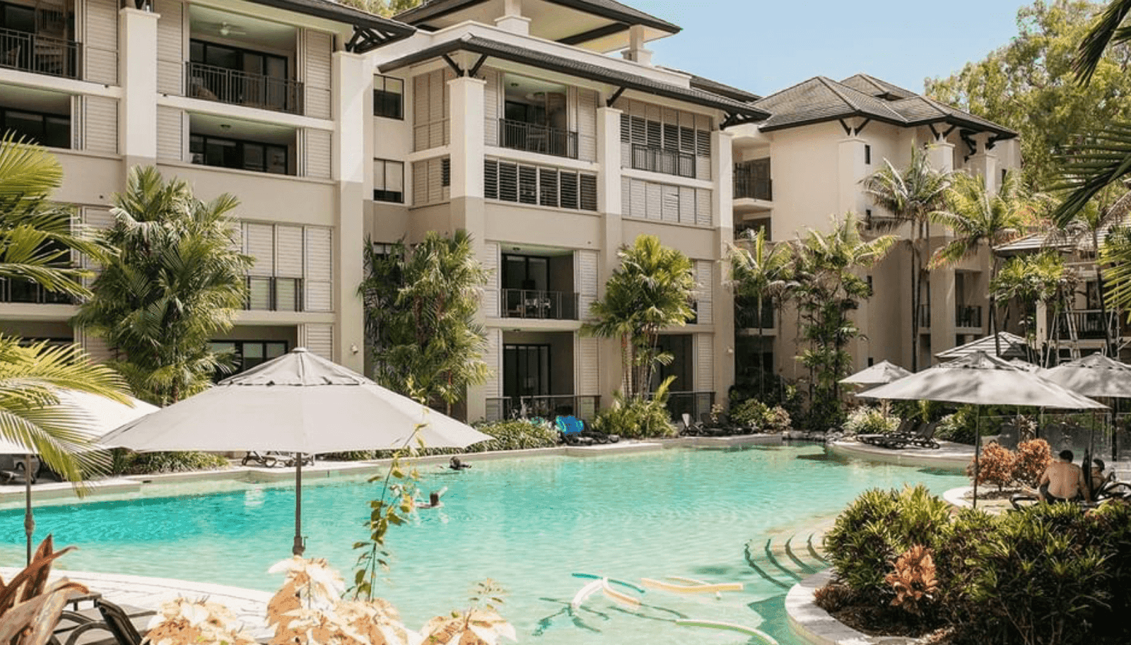 Resort buildings and outdoor swimming pool surrounded by tropical plants at Pullman Palm Cove Sea Temple Resort & Spa