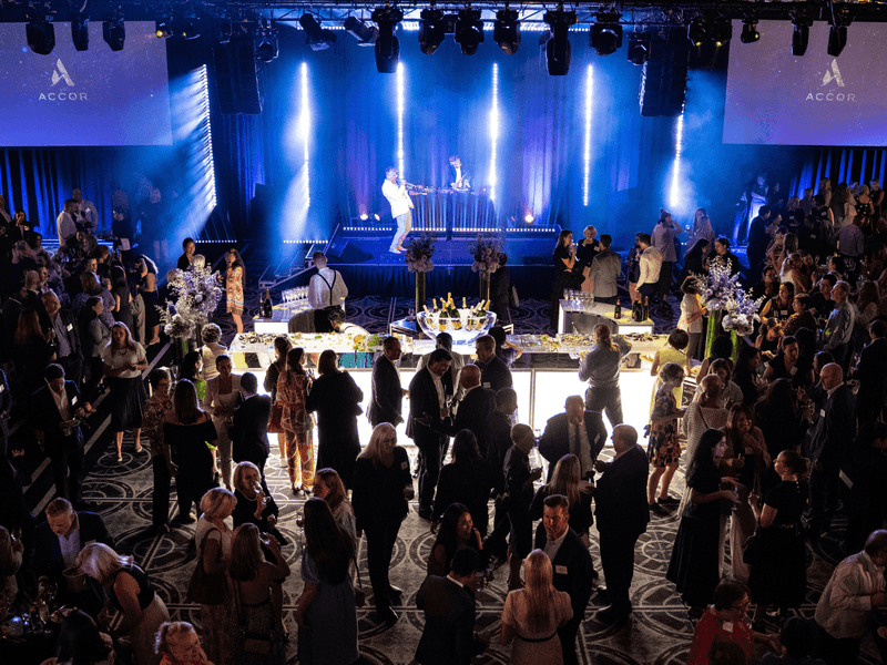 Large formal event with people in business attire, illuminated by blue stage lighting, and ACCORD branding.