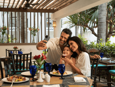 Family taking a selfie at dining table with glassware and food plates in Sunset Restaurant at at Buenaventura Grand Hotel and Spa