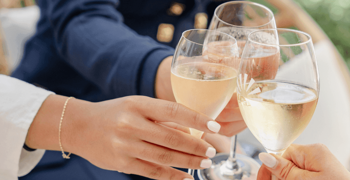 Close-up of four hands holding glasses of champagne, toasting together at Novotel Sydney Brighton Beach