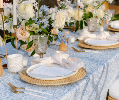 Elegant wedding table setting with blue linens, floral arrangements, plates, and glassware at Anchorage By The Sea