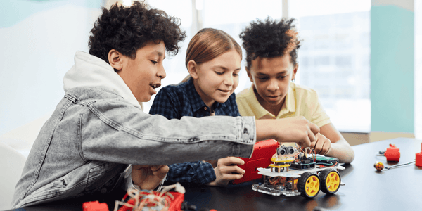 Three kids engaging with electronic building blocks and a robot on the table at The Diplomat Resort