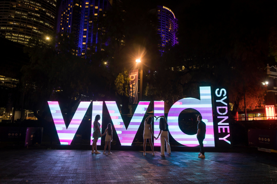 People posing by Vivid Sydney sign near Amora Hotel Sydney
