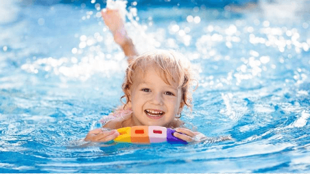 A kid swimming with a floating board at Live Aqua Resorts