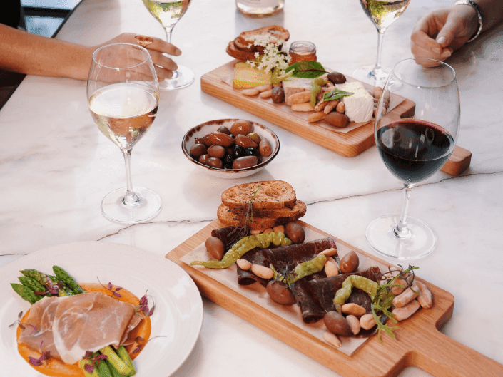 Table set with wine glasses and a plate of asparagus with prosciutto served in Silo Bar at Amora Hotel Jamison Sydney