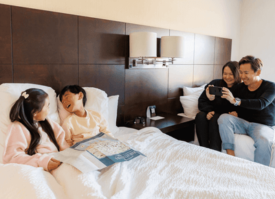 Family with kids looking at a city map on a comfortable plush king bed during a relaxing vacation at Rodd Royalty