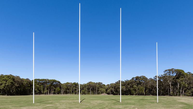 Four white goal posts rising on an AFL field bordered by trees at the Novotel Sunshine Coast Resort