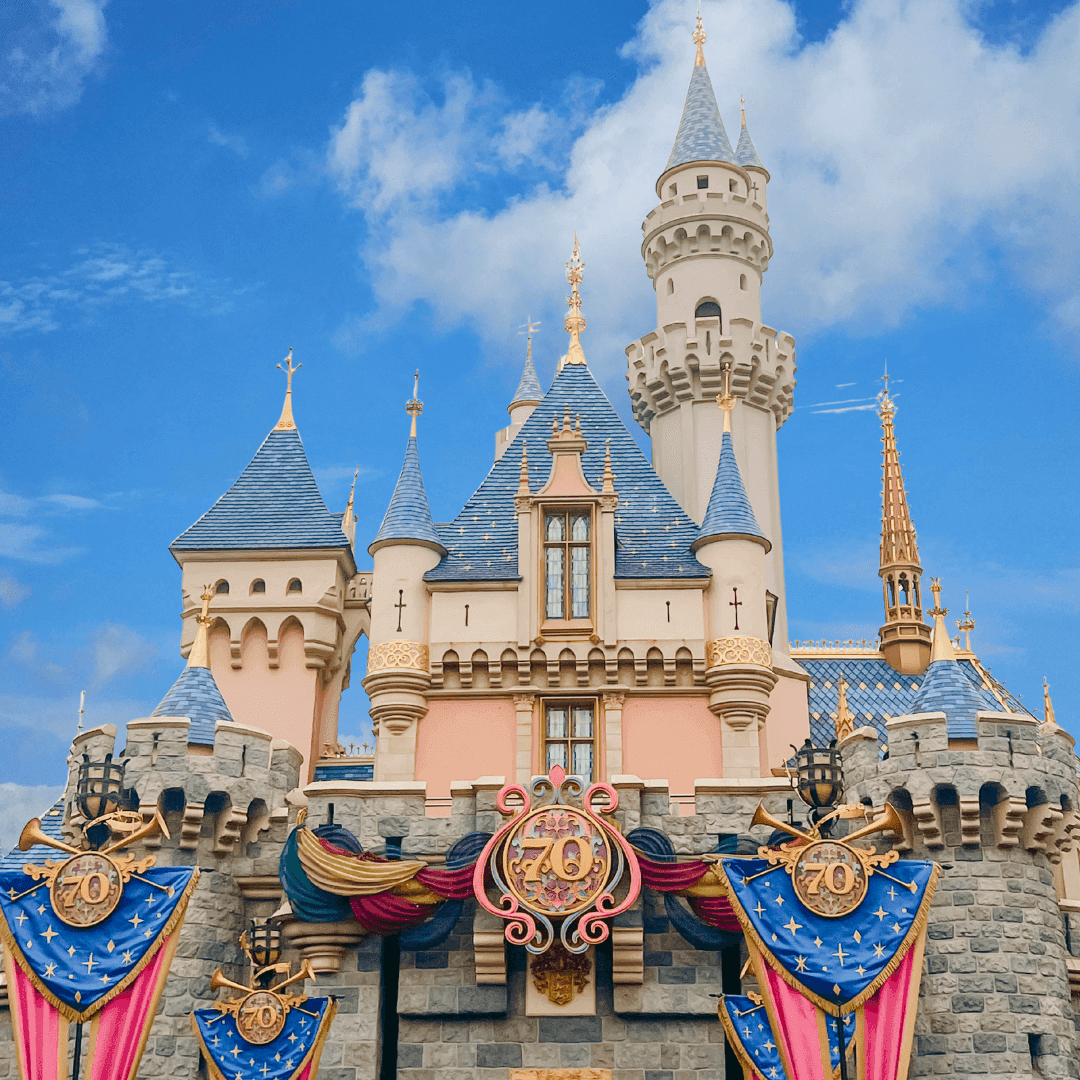 A fairytale castle with multiple turrets and towers under a blue sky with clouds.