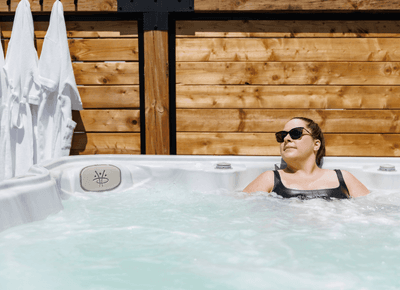 Woman in black swimwear relaxing inside a bubbling outdoor hot tub before a wooden fence at Rodd Moncton