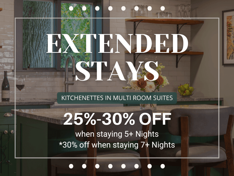 color photo of kitchenette with green cabinets, marble countertops & comfy island chairs. photo displays promo details. 