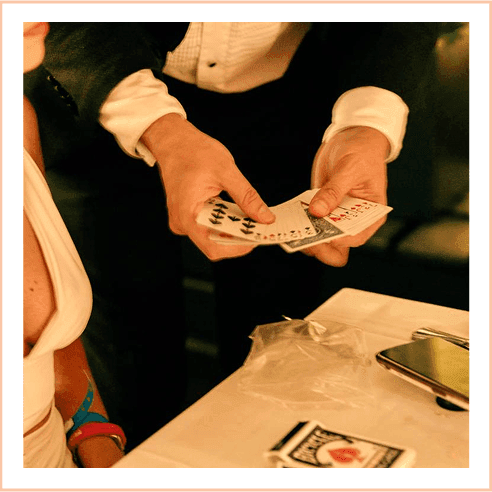 Magician's hands shuffling and performing a card trick at a table with a white tablecloth at The Plymouth Hotel South Beach