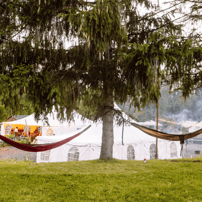 Firelight Camps in Ithaca, NY, featuring a large event tent and hammocks strung between trees at La Tourelle Hotel and Spa