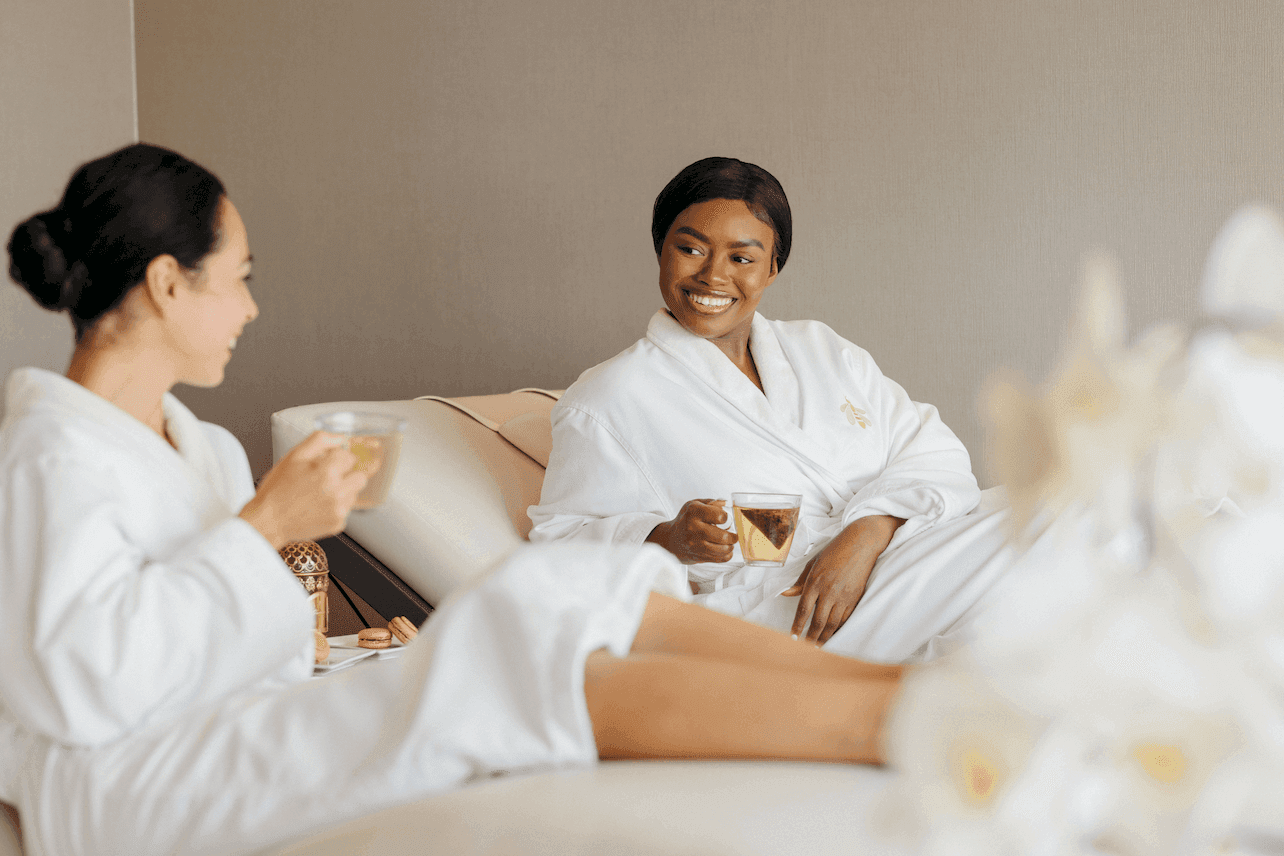 Deux femmes en robe blanche se détendent en buvant du thé dans le spa Guerlain de l'hôtel X Toronto