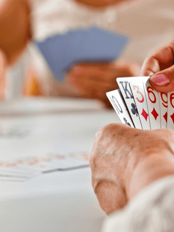 Hands holding a fan of playing cards during a leisure game, played by guests at Warwick Hotels and Resorts