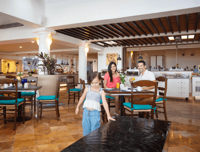 Frutas y Flores Restaurant with guests sitting at table and an open kitchen in the background at Buenaventura Grand Hotel and Spa