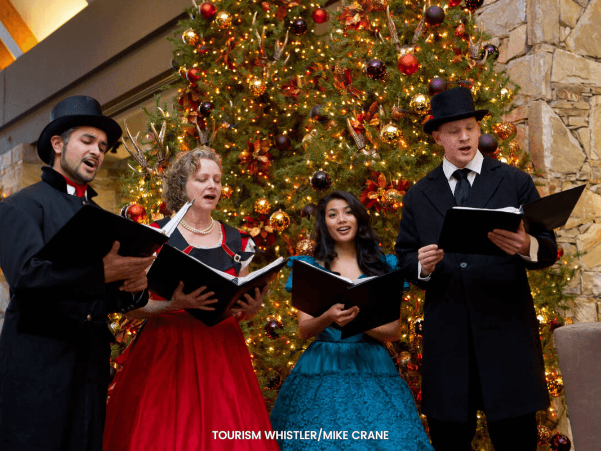 Whistler Singers group singing carols with a Christmas backdrop at Blackcomb Springs Suites