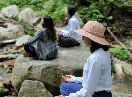 Women sitting on rocks meditating near Honor's Haven Retreat