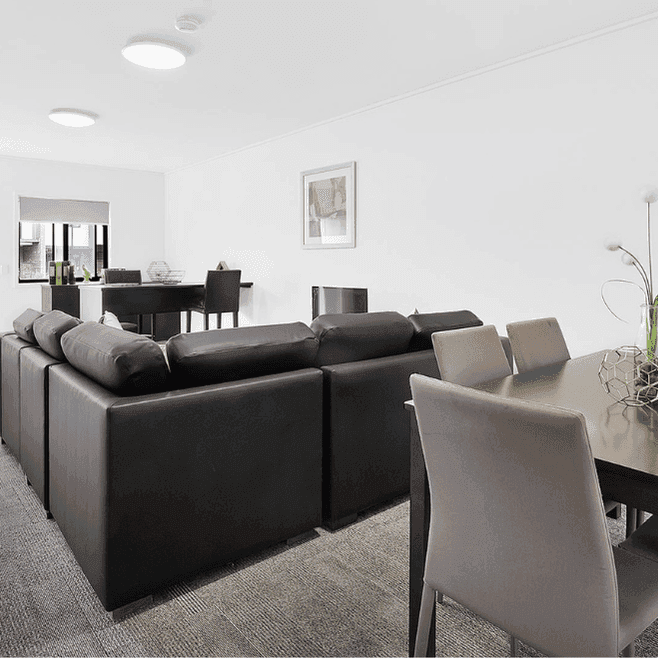 Modern open-plan living area with dark sofa, dining table, and bright natural light at Springfield Central