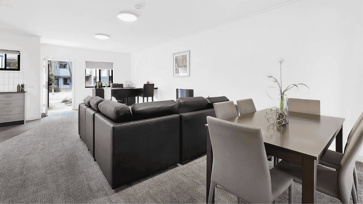 Modern open-plan living area with dark sofa, dining table, and bright natural light at Springfield Central