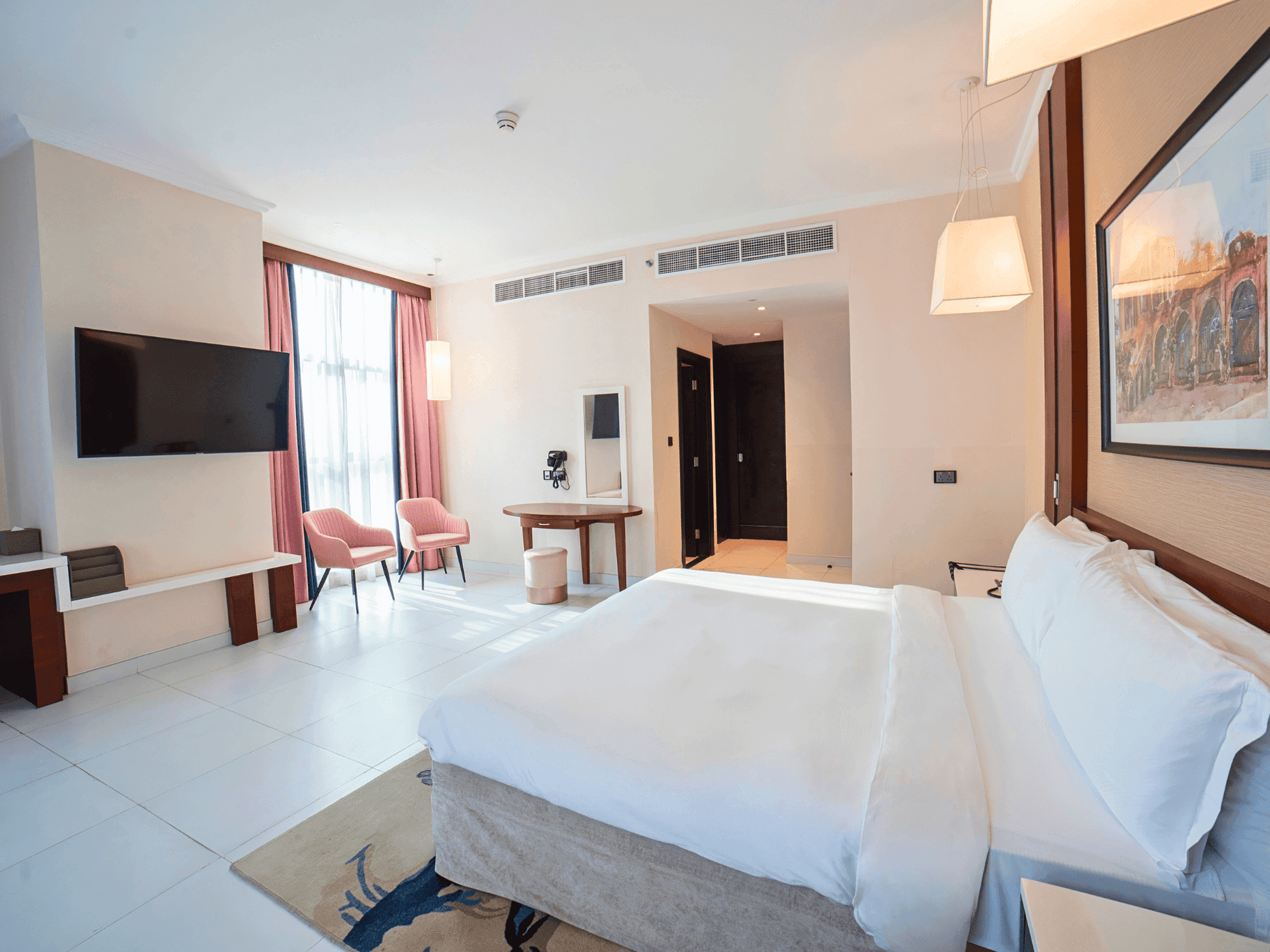 Elegant Executive Suite with large bed, modern decor, and city view at Asma Hotel, Dubai.