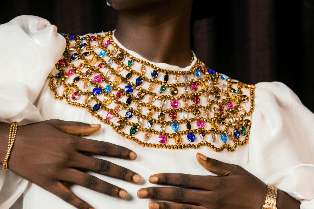 Close-up of a guest wearing a necklace with multicolored gems, placed by a dark curtain at Hotel Westminster Paris