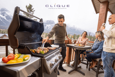 Friends grill steaks and vegetables on a balcony at Falcon Crest Lodge, enjoying wine and a stunning mountain view