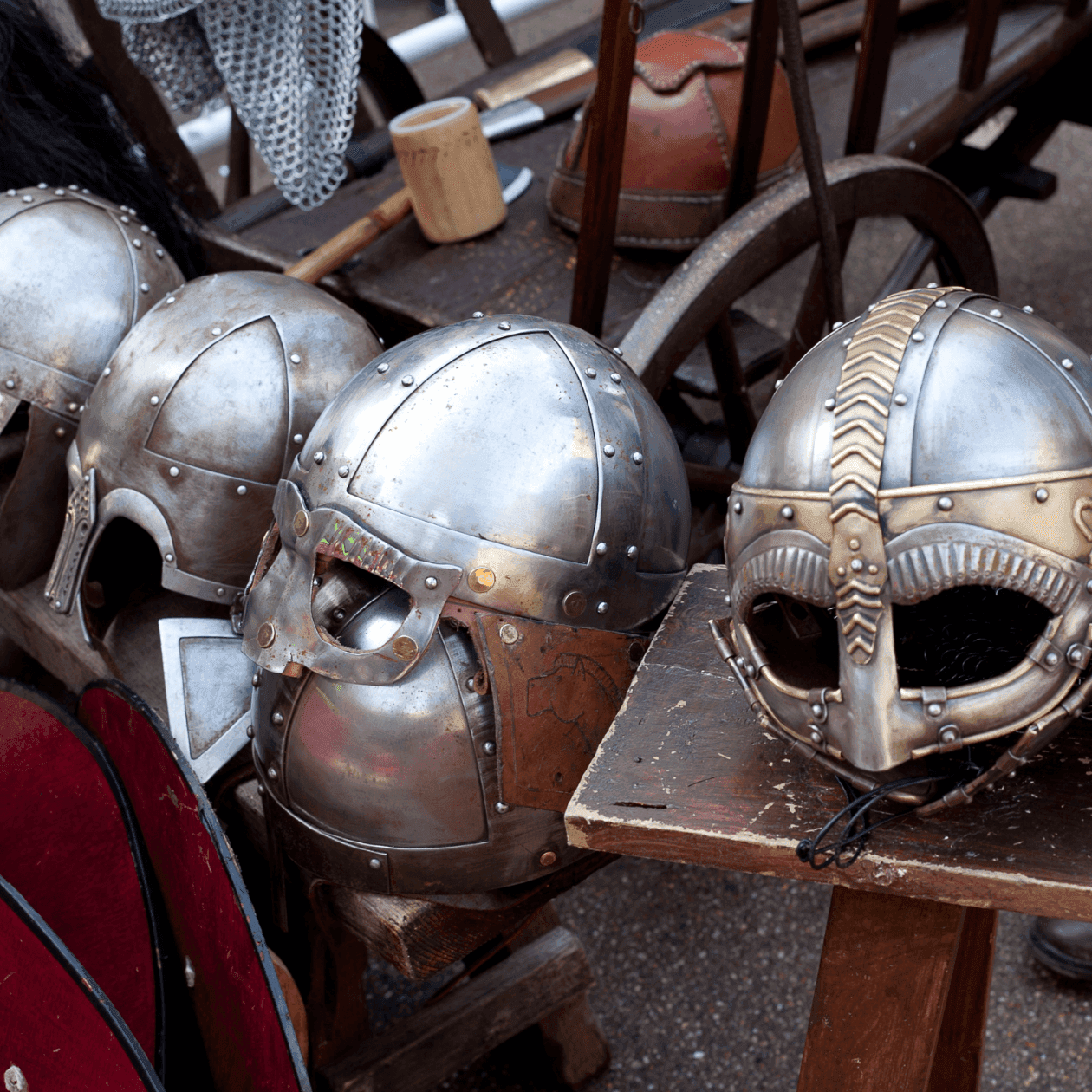 Several metallic Viking helmets and shields displayed on a wooden table in Harvest Festival at Applecrest near The Exeter Inn