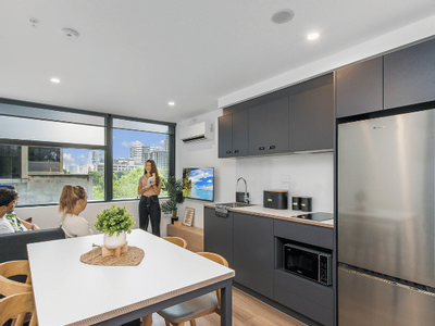 Modern living space with dining area, kitchen, and large windows showing city view.