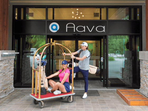 Couple on a luggage trolley by a hotel entrance, Aava Whistler