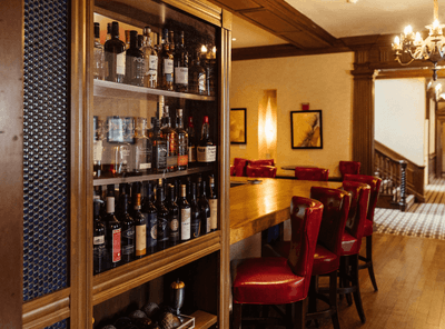 Well-stocked bar with bottles of wine and spirits, a cozy seating area at Epoch Restaurant & Bar in The Exeter Inn