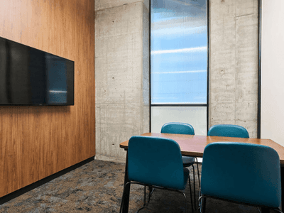 Study room with wood paneling, blue chairs, a wooden table, and a mounted TV.