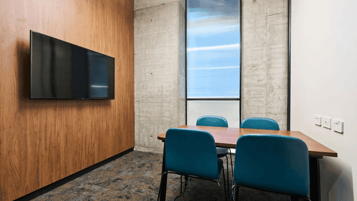 Study room with wood paneling, blue chairs, a wooden table, and a mounted TV.