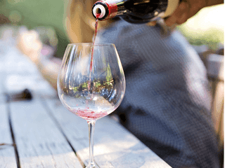 Red Wine Pouring into a Glass on the Wooden Table in the Inn at Willow Grove