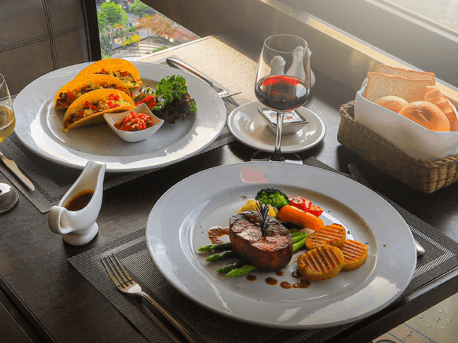 A table set with two plates of delicious food and a glass of wine, ready to be enjoyed.
