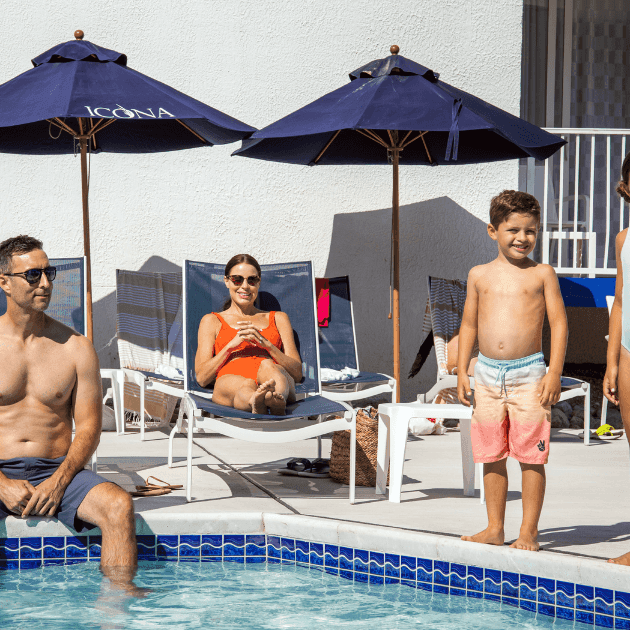 Father, mother, and two children relaxing next to Mahalo pool
