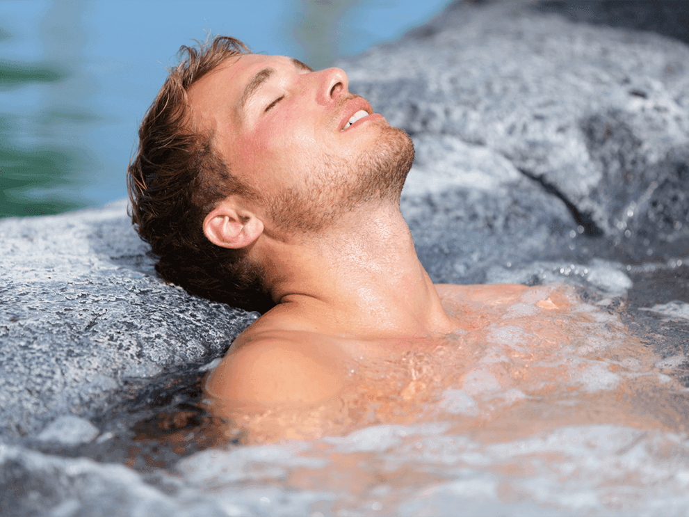 Man enjoying a hot tub while relaxing on a sunny day at Juniper Hill Inn