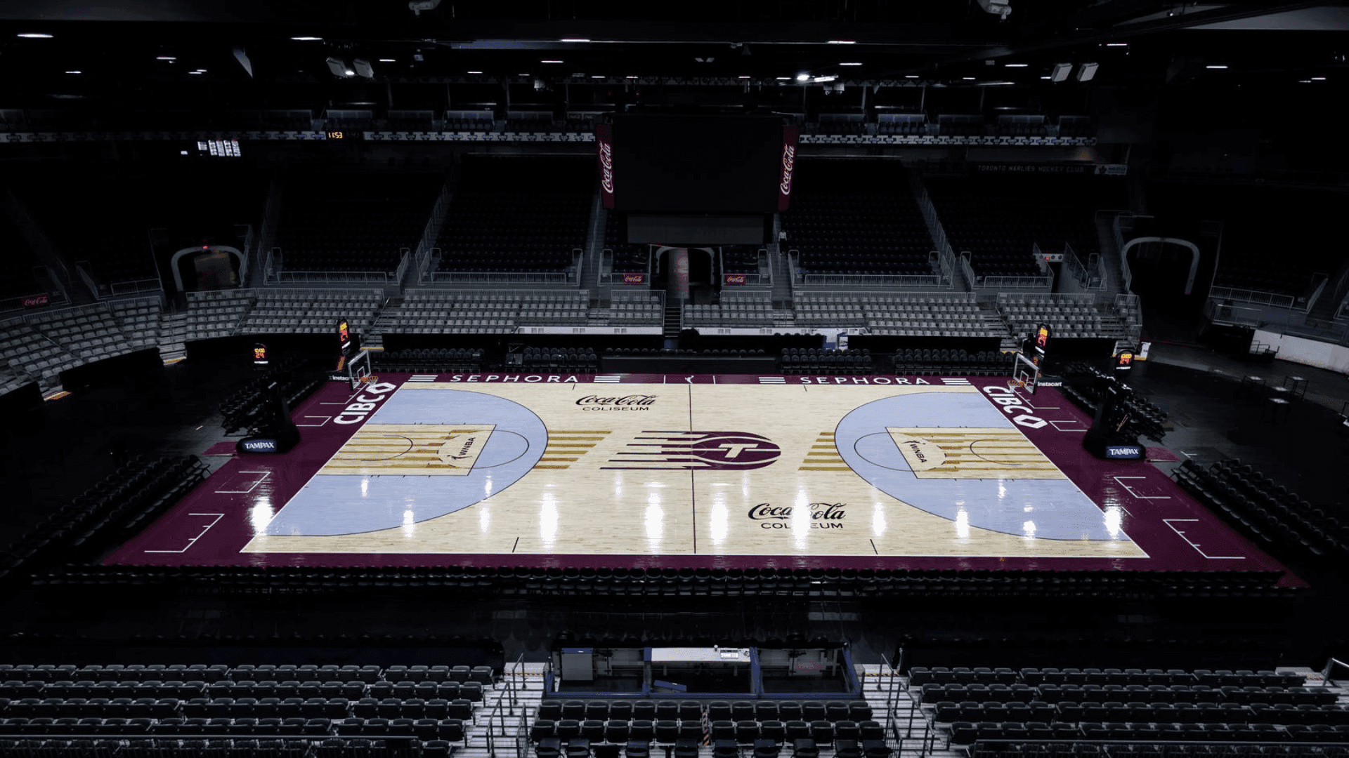 Basketball court surrounded by tiered seating under arena lights at Coca-Cola Coliseum located near Hotel X Toronto