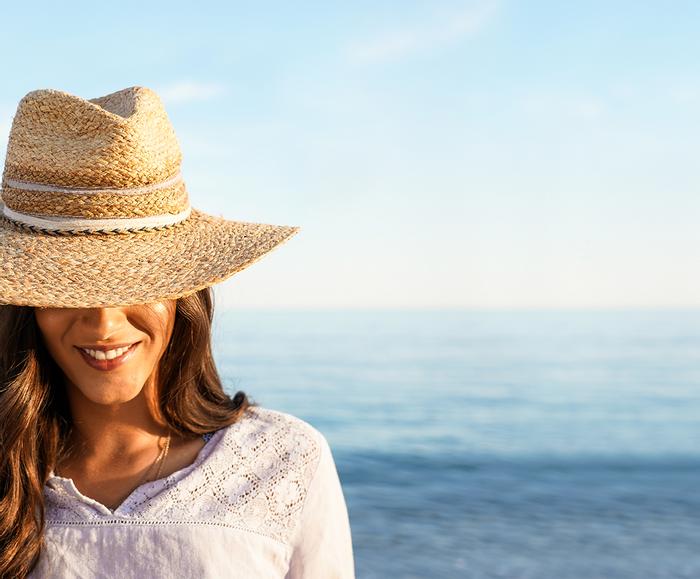 A woman wearing a hat near the beach at Falkensteiner Hotels
