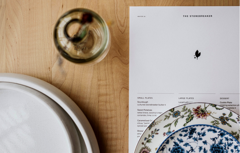 First Person perspective of sitting down at the table with a plate set and Menu