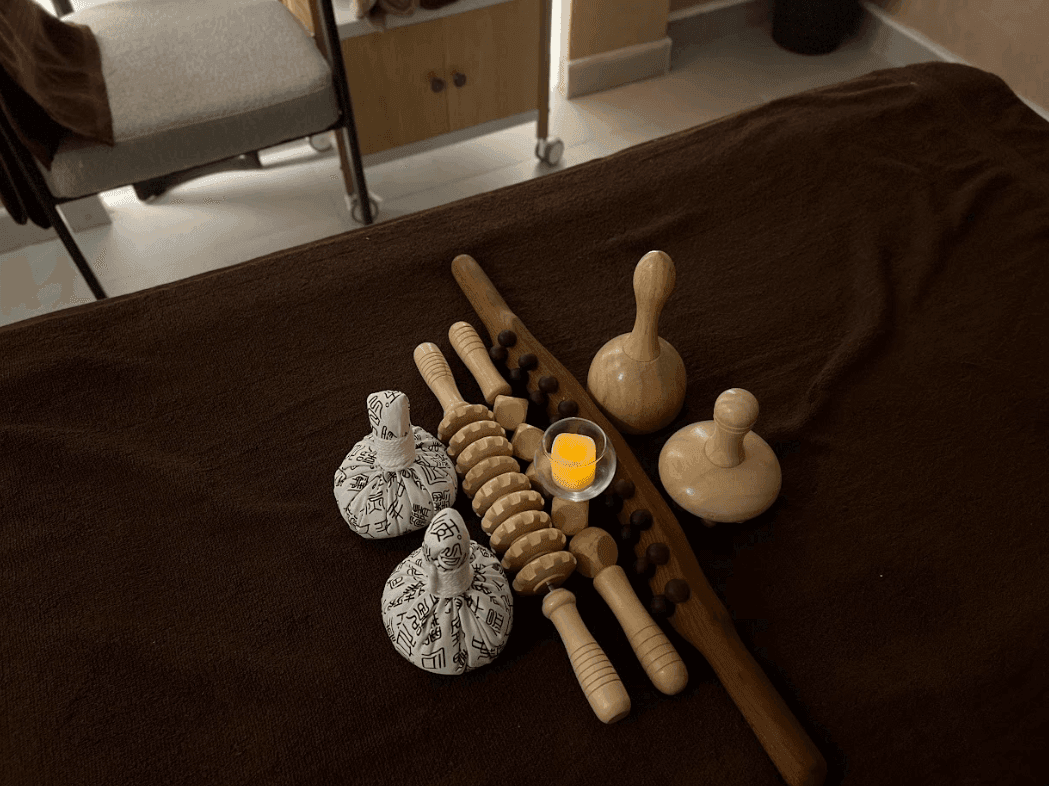 Wooden massage tools with herbal compresses on a brown towel at Warwick Al Jubail