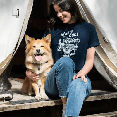 Woman sitting with a smiling golden dog at the entrance of a canvas glamping tent at La Tourelle Hotel and Spa