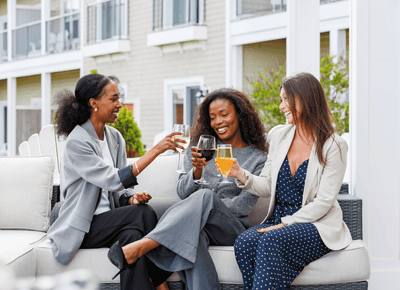 Three women enjoying drinks together on an outdoor patio during a social event at Rodd Crowbush Golf & Beach Resort