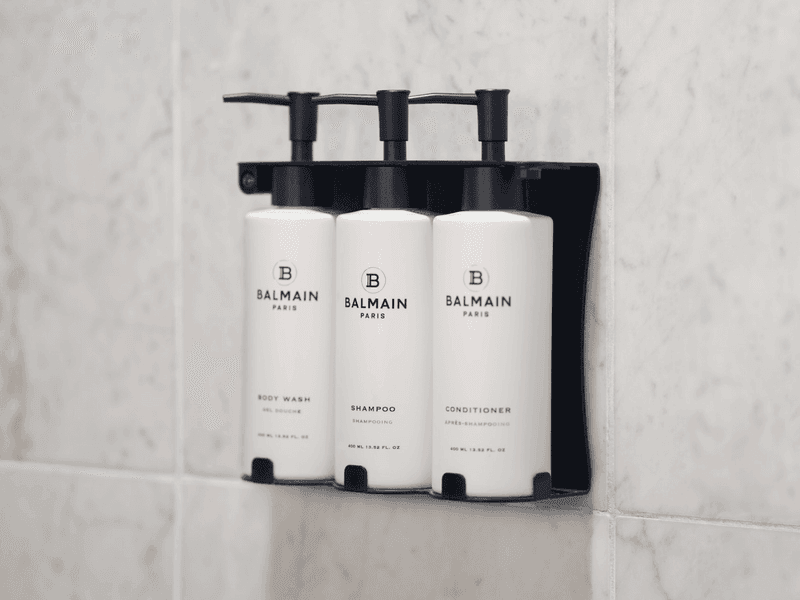 Balmain Paris luxury hotel toiletries - three pump bottles mounted on marble bathroom wall