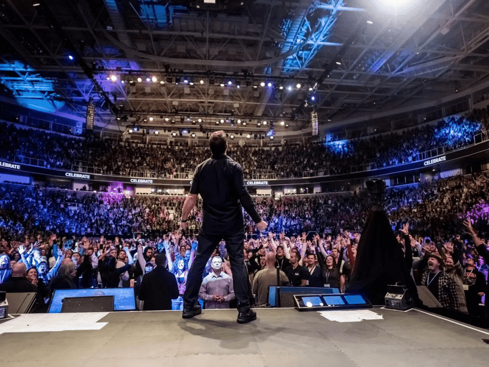 A man on stage in front of a large audience during the Fortuna One Global Summit 2026.