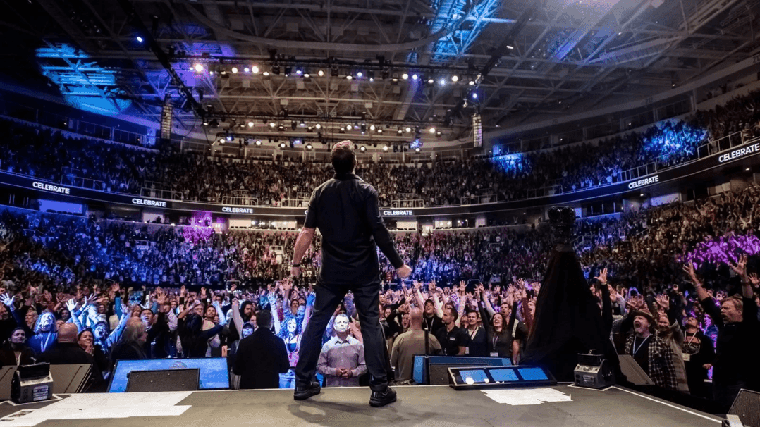 A man on stage in front of a large audience during the Fortuna One Global Summit 2026.