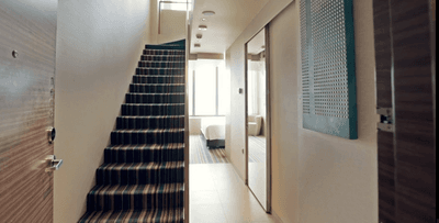 The Loft apartment interior with a striped carpeted staircase on the left at One Farrer Hotel