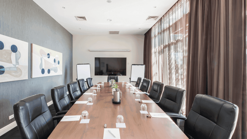 Boardroom One with a long table, black chairs, and abstract art on the wall at Mercure Kooindah Waters