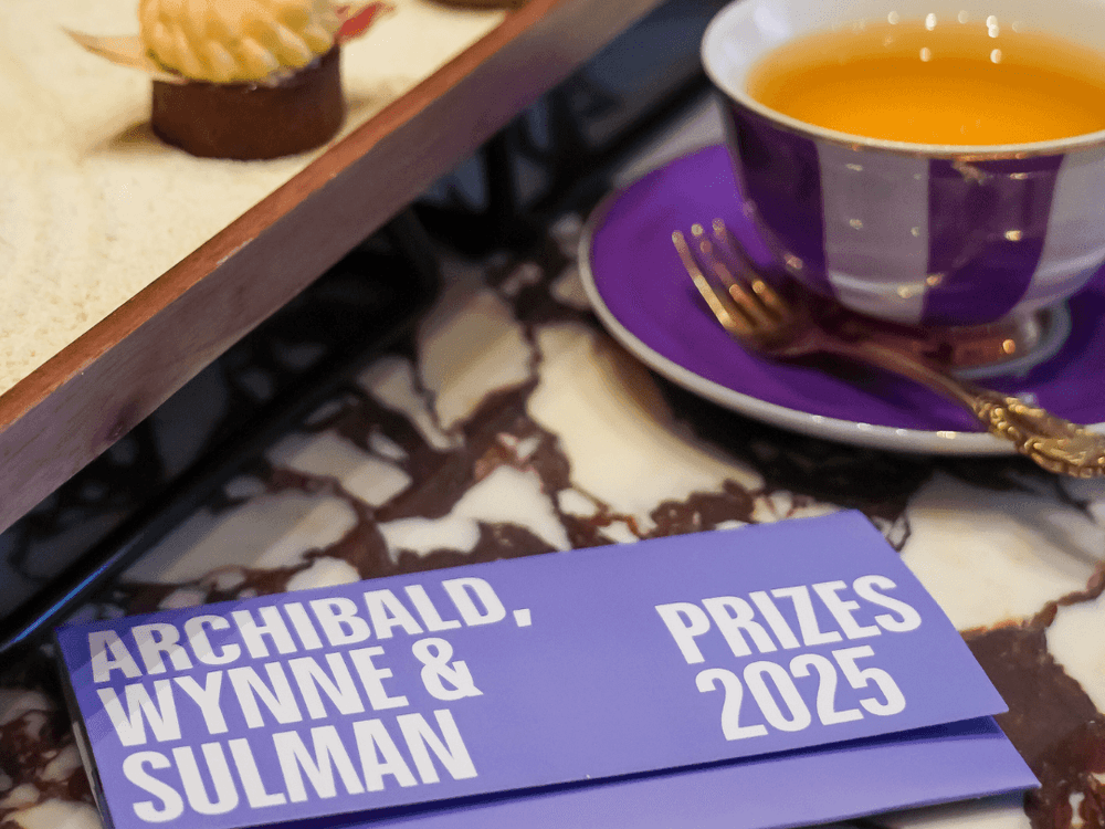 Gourmet chocolate dessert platter with tea cup and Archibald, Wynne & Sulman Prizes 2025 program book
